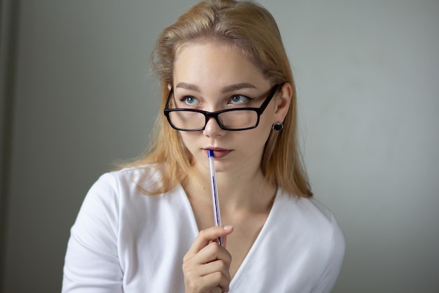 Portrait of the young thinking business woman looking up