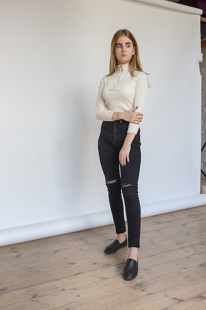 Portrait of young thoughtful teen model wearing white sweater and black jeans