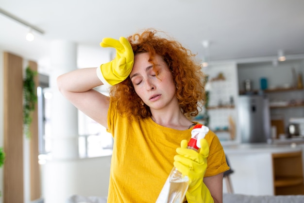 Portrait of young tired woman with rubber gloves resting after cleaning an apartment Home housekeeping concept