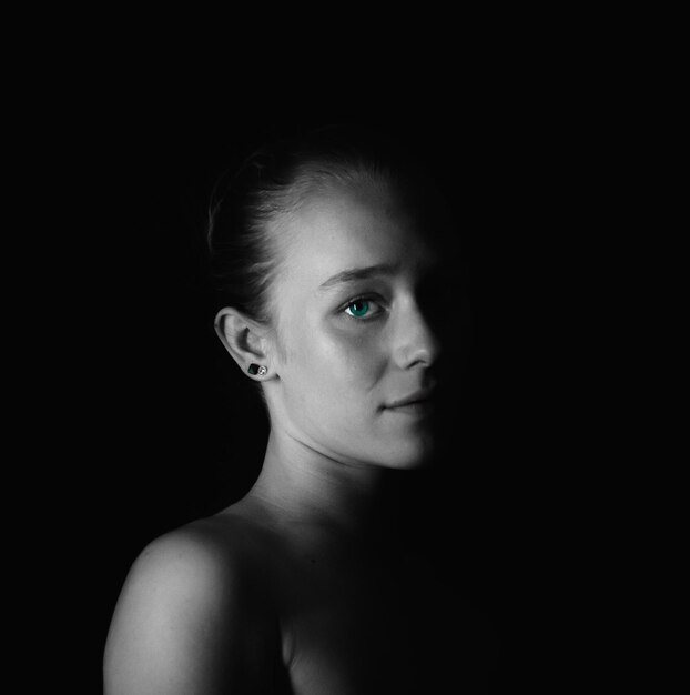 Portrait of young woman against black background