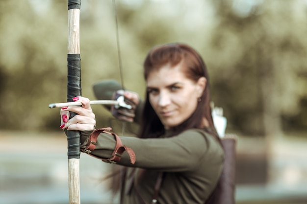 Portrait of young woman archery on forest background