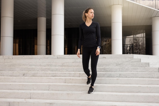 portrait of a young woman in a black tracksuit doing gymnastics