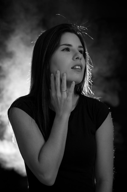 Portrait of a young woman in black and white with black background and smoke