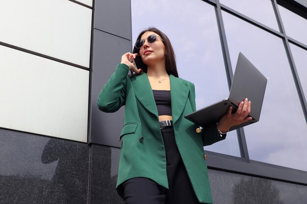 Portrait of a young woman in a business suit with a laptop and a mobile phone