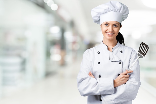 Portrait of young woman chef on background