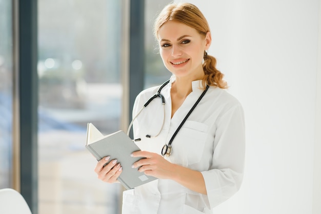 Portrait of young woman doctor with white coat standing in hospital