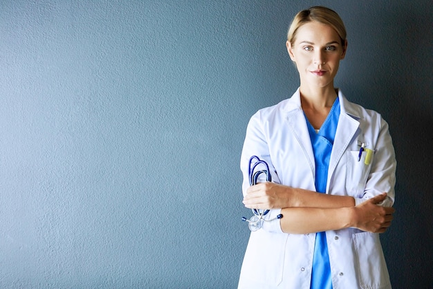 Portrait of young woman doctor with white coat standing in hospital