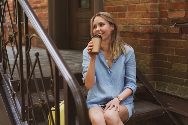 Portrait of a young woman drinks coffee the city street