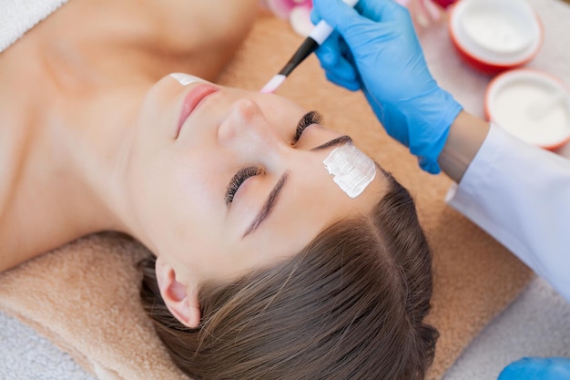 Portrait of a young woman getting spa treatment and face massage at beauty salon