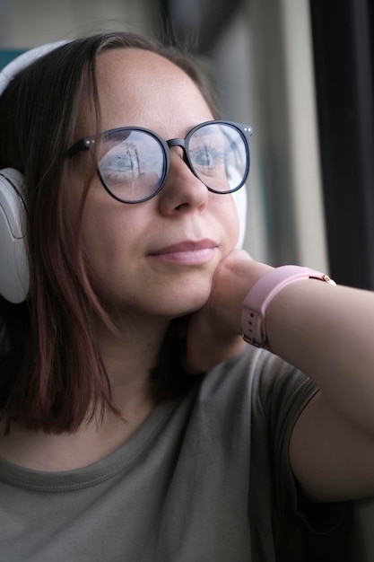 Portrait of young woman in glasses riding on train looking at nature Close up