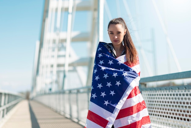 Portrait of young woman holding american flag outdoors