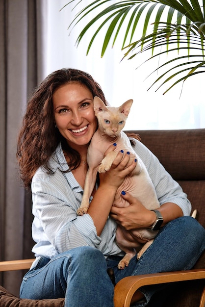 Portrait of young woman holding cute cat with blue eyes Female hugging her cute short hair kitty Background copy space close up Adorable domestic pet concept