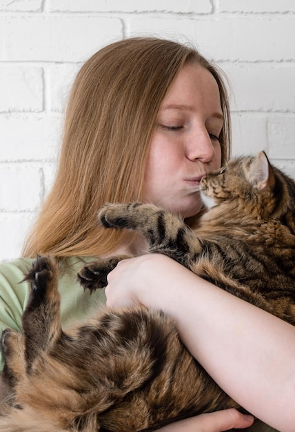 Portrait of young woman holding cute cat with green eyes girl kiss cat