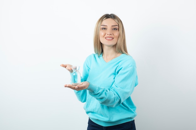 Portrait of young woman holding glass pitcher of water in hand