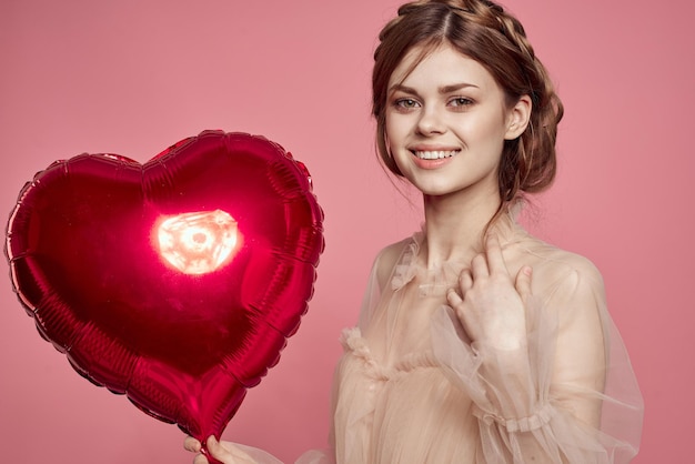 Photo portrait of young woman holding heart shape against yellow background