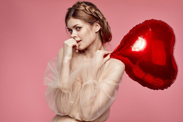 Photo portrait of young woman holding heart shape against yellow background