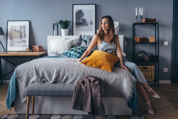 Portrait of young woman at home on bed