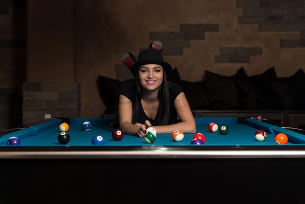 Portrait Of A Young Woman Lying On The Table And Playing Billiards