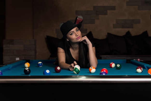 Portrait Of A Young Woman Lying On The Table And Playing Billiards