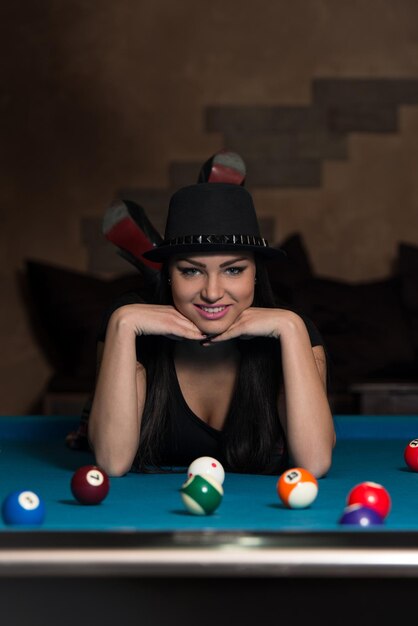 Portrait Of A Young Woman Lying On The Table And Playing Billiards