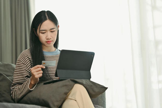 Portrait of young woman making orders via the Internet on digital tablet or paying by credit card