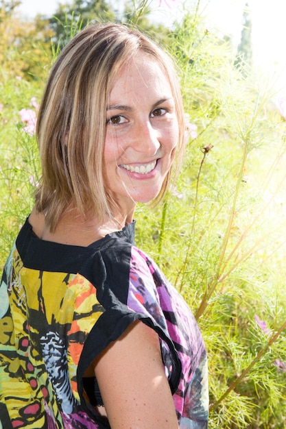 Photo portrait of young woman in park with sun and flowers