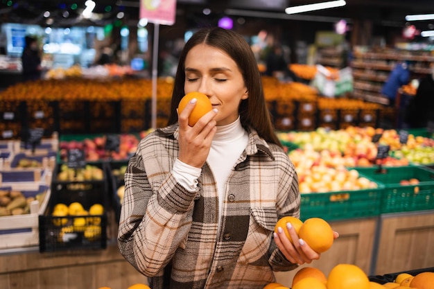 Portrait of a young woman picking oranges in a supermarket