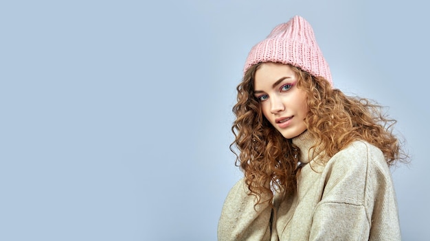 Portrait of a young woman in a pink hat on a gray background