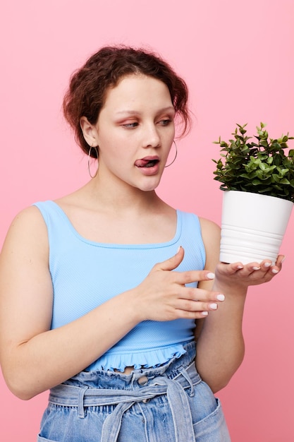 Portrait of a young woman potted flower posing plant pink background unaltered