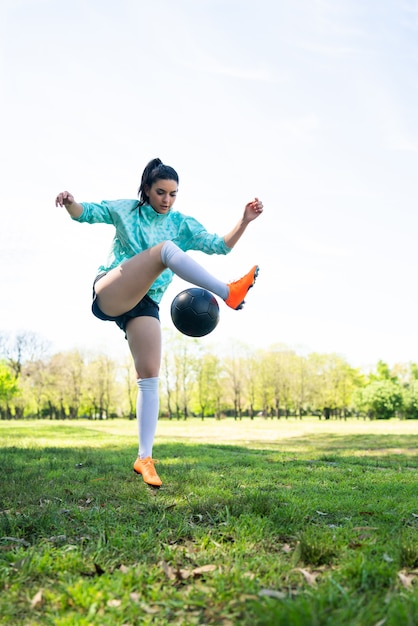 Portrait of young woman practicing soccer skills and doing tricks with the football ball. Soccer player juggling the ball.