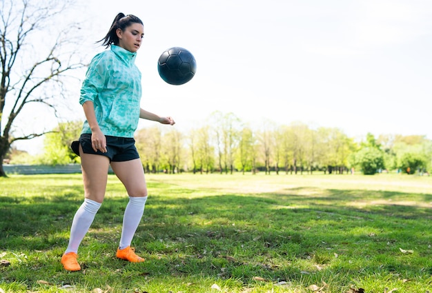 Portrait of young woman practicing soccer skills and doing tricks with the football ball. Soccer player juggling the ball.