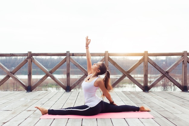 Portrait of young woman practicing yoga pose outdoors on nature