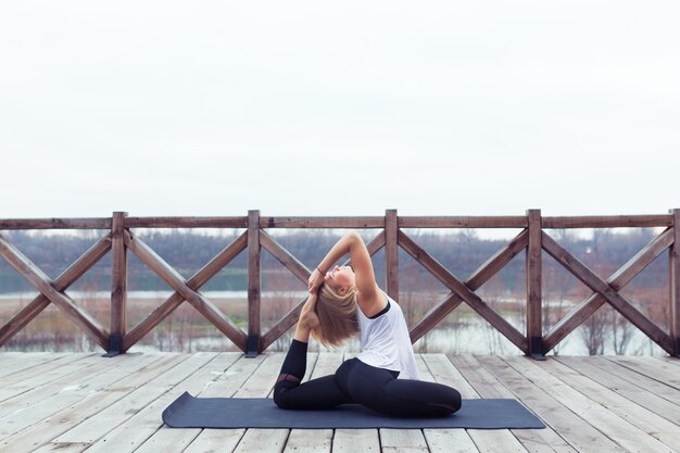 Portrait of young woman practicing yoga pose outdoors on nature