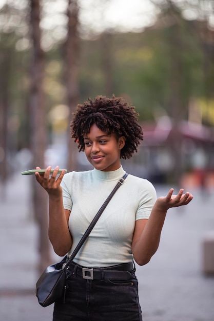 Portrait of a young woman recording voice messages on a smartphone Smiling girl texting on a smartphone while walking in the city