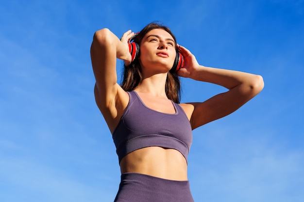 Portrait of a young woman in red headphones An athlete during a summer workout outside