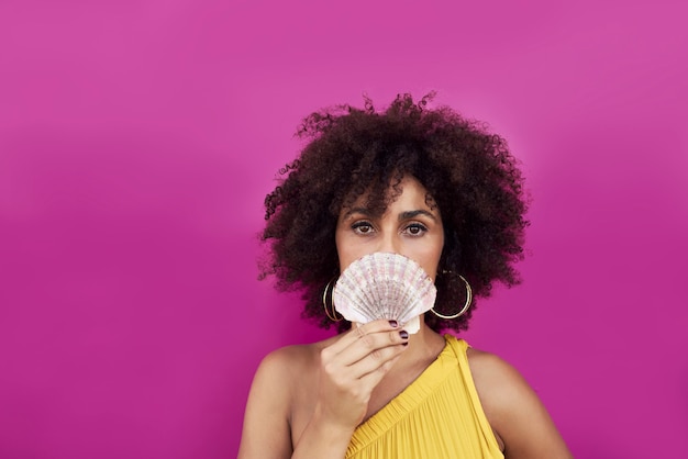 Portrait of a young woman, she is holding a seashell in her hands.