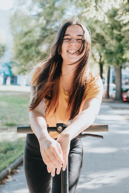 Portrait of young woman smiling leaning on an electric scooter in the cityResting after an entire day of visiting all places of interestHaving fun riding publiceco and rechargeable transport