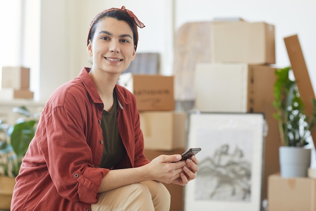 Portrait of young woman smiling while using her mobile phone she waiting for loaders