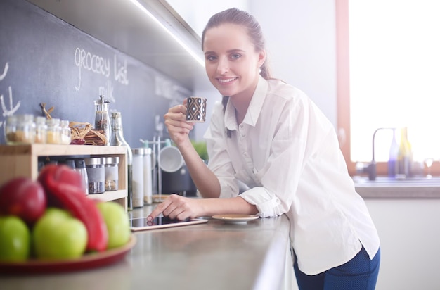 Portrait of young woman standing against kitchen background