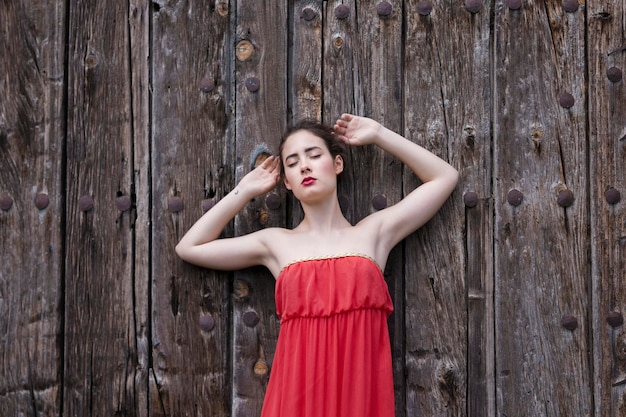 Photo portrait of a young woman standing against wooden wall