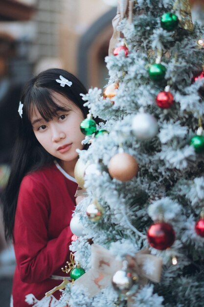 Portrait of young woman standing by christmas tree