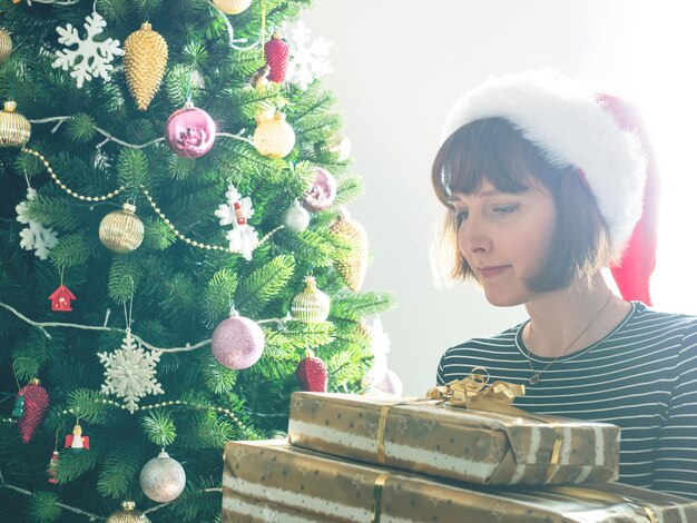 Portrait of young woman standing by christmas tree