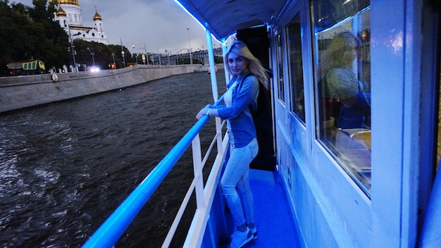 Photo portrait of young woman standing on ferry boat in canal at dusk