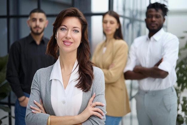 Portrait of a young woman standing in an office with colleagues in the background