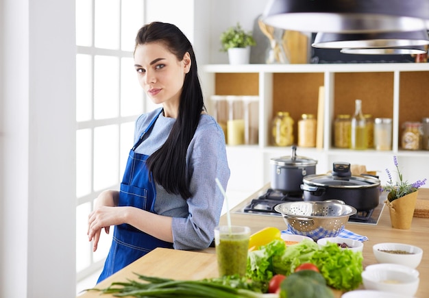 Portrait of young woman standing with arms crossed against kitchen background