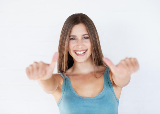 Portrait young woman and thumbs up for celebration feedback and lady isolated on white studio background Female girl and gesture for success goal and winner with motivation wellness or backdrop