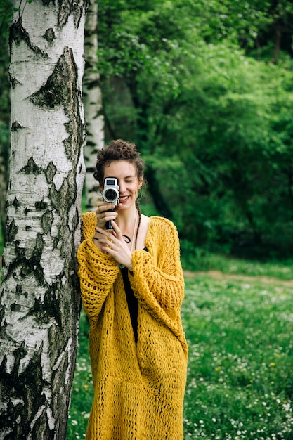 Portrait of young woman using a vintage cinema camera in a park