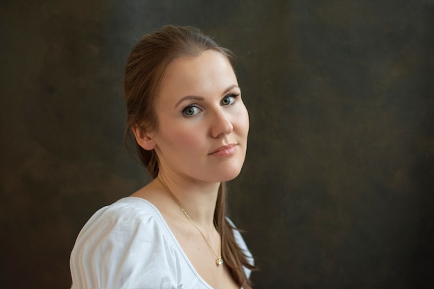 Portrait of young woman in white blouse and dark background