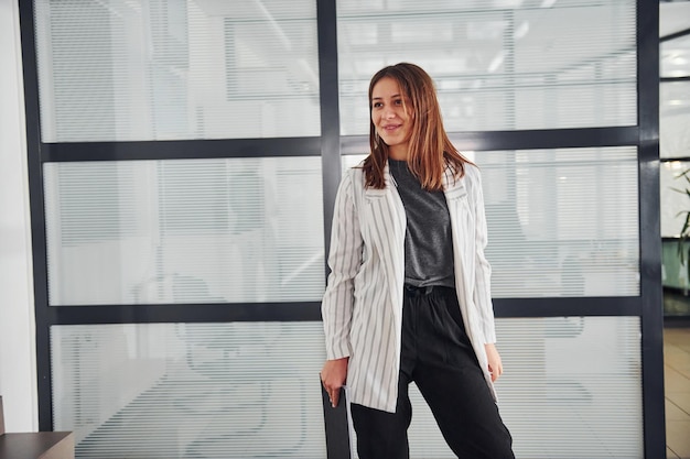 Photo portrait of young woman in white formal clothes that standing indoors.