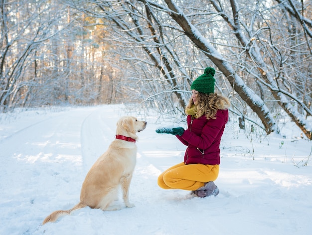 Portrait of young woman in winter park playing with her dog